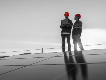 Specialist technician professional engineer with laptop and tablet maintenance checking installing solar roof panel on the factory rooftop under sunlight. Engineers team survey check solar panel roof.